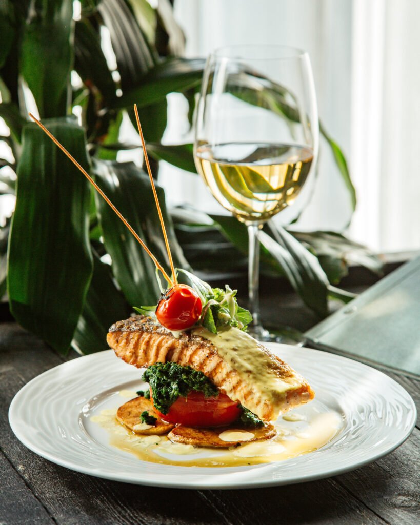 fried salmon steak placed over potato rings tomato and broccoli